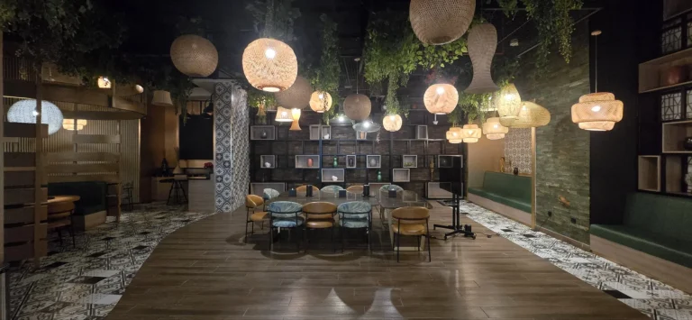 The restaurant as found: rattan pendants, hanging greenery and a display shelf wall