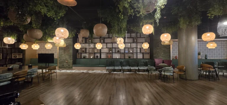 The existing lounge, green banquettes beneath woven pendants