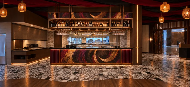 The bar, its crimson front carrying a painted crescent artwork beneath a brass gantry